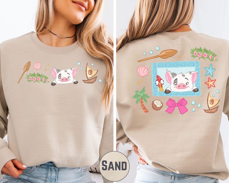 a woman wearing a beige sweater with a colorful and whimsical design on the back. The design includes a pig, a boat, a palm tree, and various other elements, creating a playful and cheerful appearance.