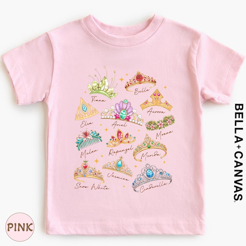 A pink t-shirt with a design of various crowns and tiaras, each with a unique color and style.