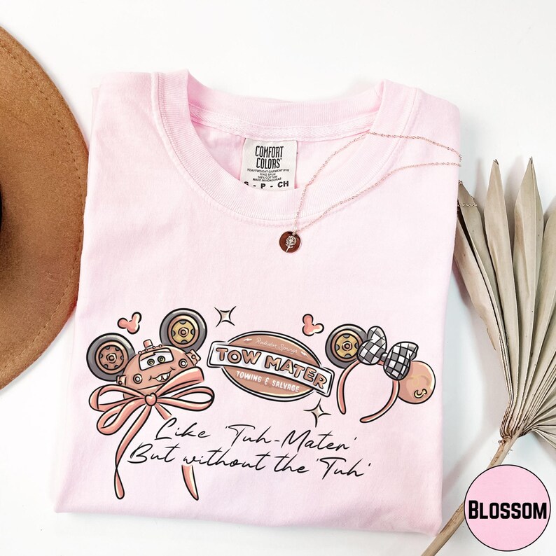 a pink t-shirt with a cartoon character design, a necklace, a hat, and some decorative elements on a white background.