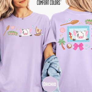 two women wearing purple t-shirts with cartoon pig designs and various other colorful elements.