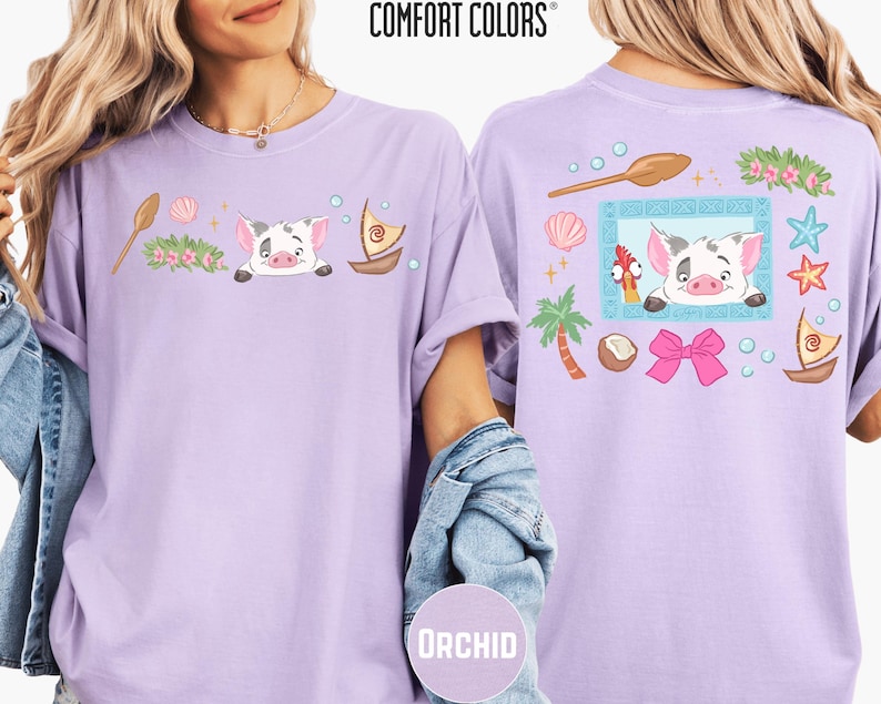 two women wearing purple t-shirts with cartoon pig designs and various other colorful elements.