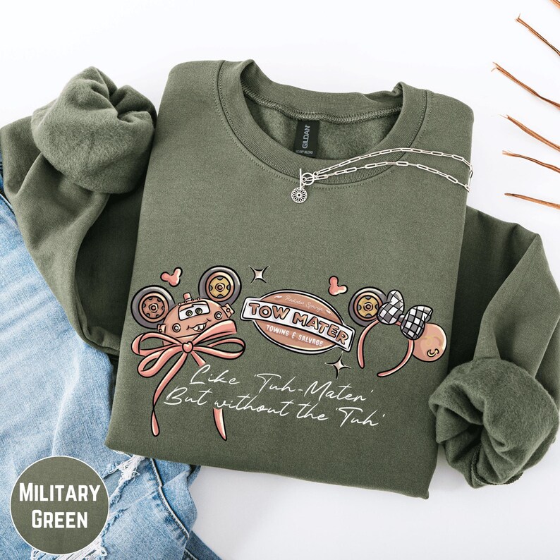 A military green sweatshirt with a graphic design featuring a tow truck and the text "TOW MATTER" and "Like Tuh-Matter, But without the Tuh!"