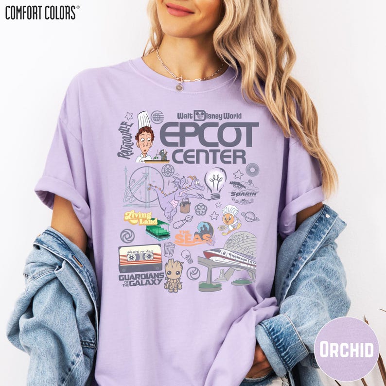 A woman wearing a purple t-shirt with various Disney-themed graphics and text, including a chef, a rocket ship, and other iconic elements associated with the EPCOT Center.