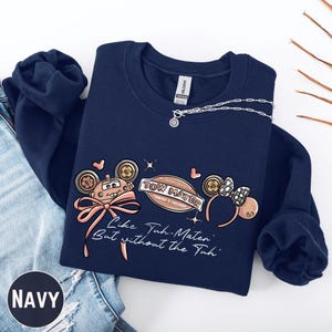 Navy sweatshirt with a graphic design featuring cartoon-style characters and text.