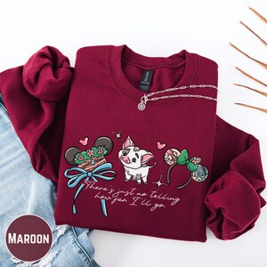 A maroon-colored sweatshirt with a Disney-themed graphic design, including a pig, Mickey Mouse ears, and a ribbon. The text on the sweatshirt says "There's just no telling how fan I'll go".