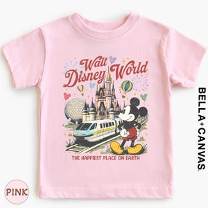 A pink t-shirt with a Disney World-themed graphic design, including Mickey Mouse, a train, and various Disney landmarks.