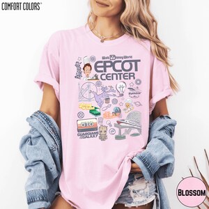 A woman wearing a pink t-shirt with various Disney-themed graphics and text, including the words 'EPCT CENTER', 'Disney World', and 'Garden of the Galaxy'.