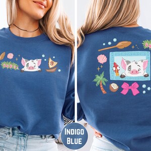 a woman wearing a blue sweatshirt with a cartoon pig design on the front and back.