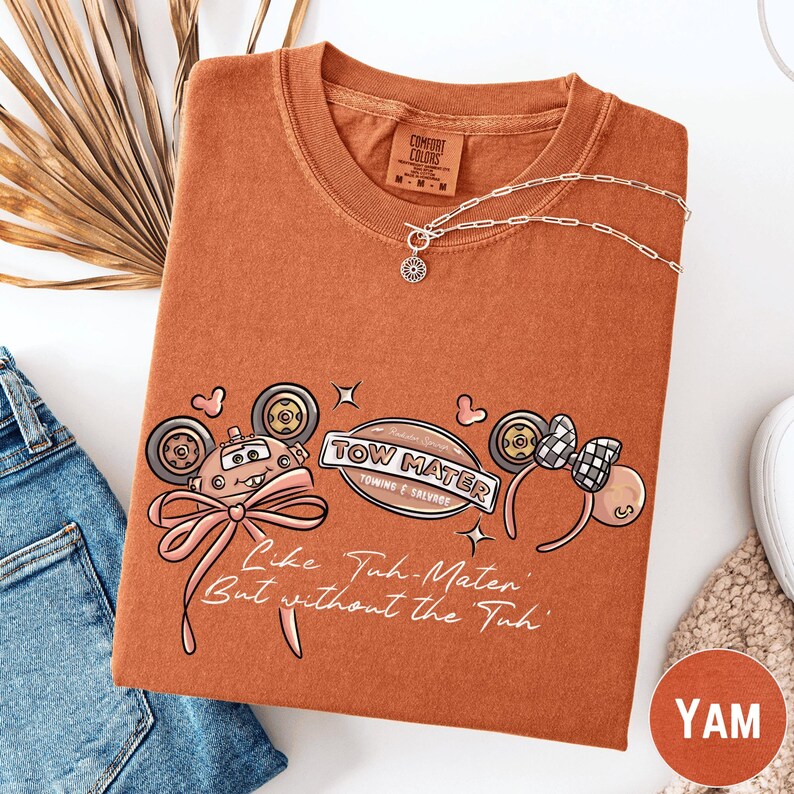a t-shirt with a cartoon-style design, a necklace, and some accessories, all laid out on a white surface.