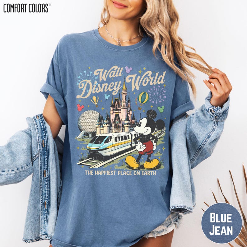 A woman wearing a blue t-shirt with a Disney World graphic and text, along with a denim jacket.