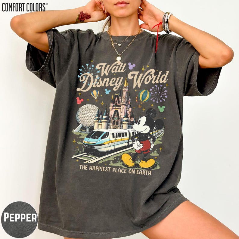 A person wearing a black t-shirt with a graphic of Mickey Mouse and a Disney World theme park.
