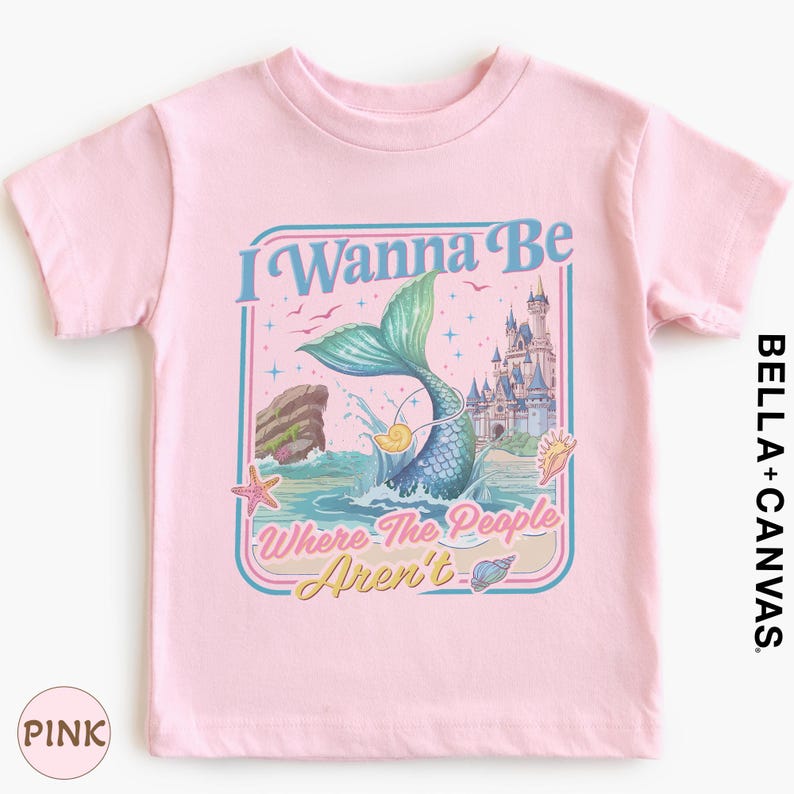 A pink t-shirt with a graphic design featuring a mermaid, a castle, and the text "I Wanna Be Where The People Aren't".