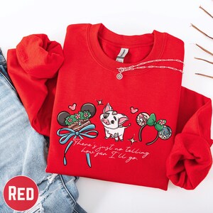 A red sweatshirt with a cartoon pig and various Disney-themed accessories, such as Mickey Mouse ears and a bow, is displayed on a white background.