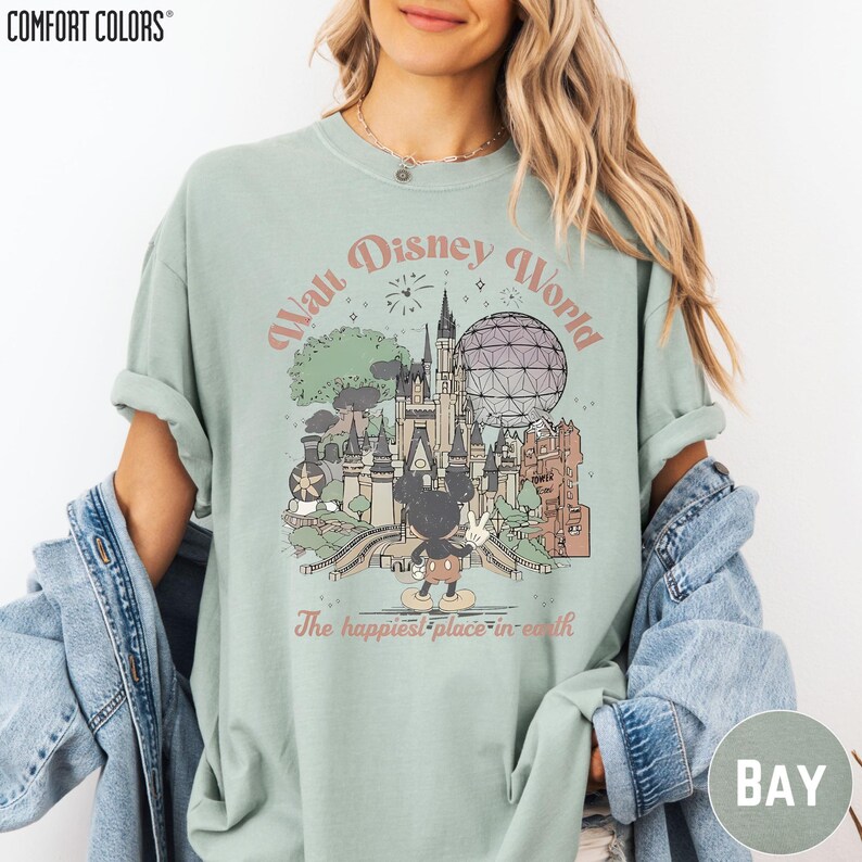 A woman wearing a green t-shirt with a graphic of Disney World and the text "The happiest place in earth" printed on it.