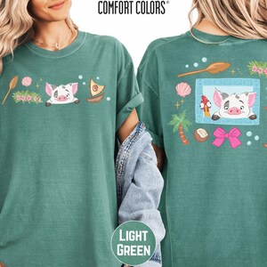two green t-shirts with colorful cartoon pig designs and various other decorative elements.