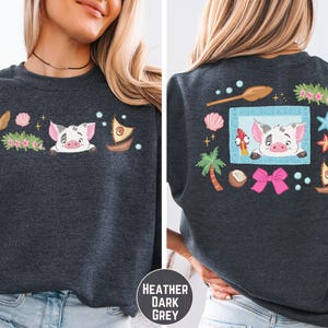 a woman wearing a gray sweatshirt with a cartoon pig design on the front and back.