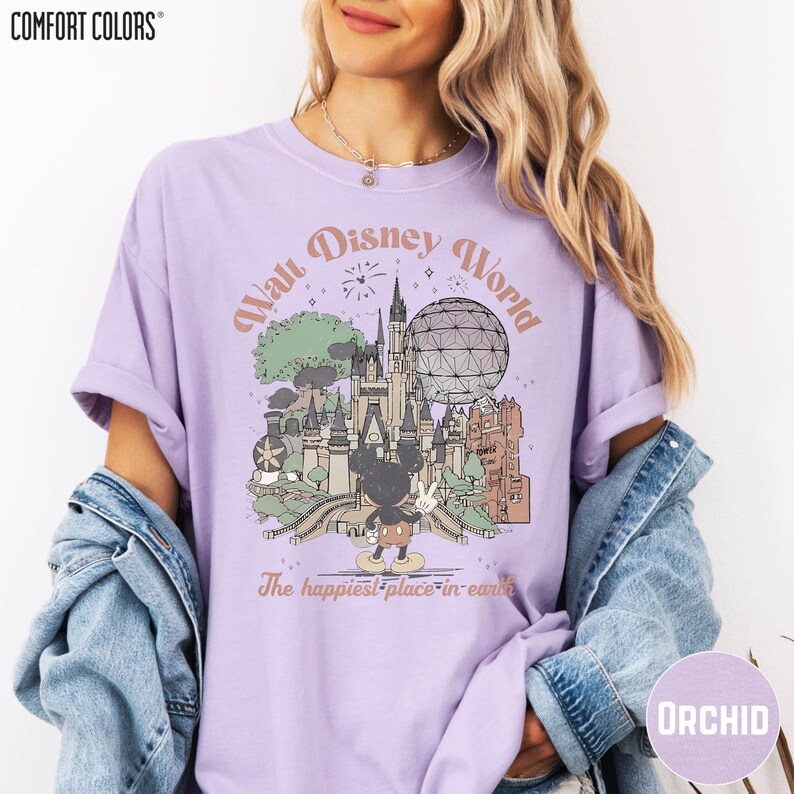 A woman wearing a purple t-shirt with a graphic of Disney World and the text "The happiest place in earth" printed on it.