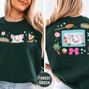 A woman wearing a green sweater with a cartoon pig and various decorative elements on the back.