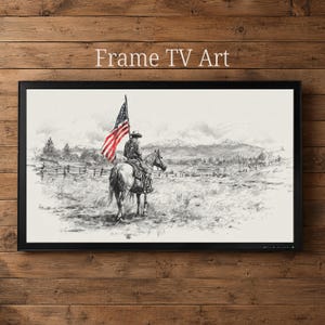 May include: Black framed TV art print featuring a cowboy on horseback holding an American flag. The black and white sketch depicts a rural landscape with mountains and a fence. The text "Frame TV Art" is at the top.