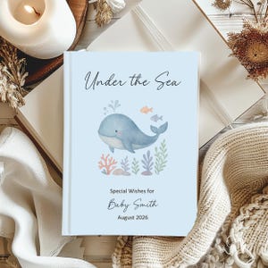 May include: A pale blue baby journal featuring the title "Under the Sea" and a watercolour illustration of a whale, fish, and seaweed. The journal is personalised with the text "Special Wishes for Baby Smith August 2026".