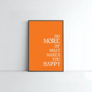 Peut inclure: Une affiche encadrée avec un fond orange et un texte blanc qui dit "DO MORE OF WHAT MAKES YOU HAPPY." L'affiche est dans un cadre noir et est affichée contre un mur blanc.