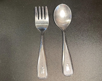 vintage "The First Years" stainless steel baby flatware set from the 1980s, featuring a textured handle with a small figure pattern
