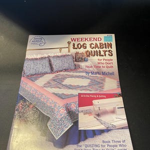 May include: A book titled "Weekend Log Cabin Quilts" by Marti Michell. The cover features a quilt with pink, blue, and white floral patterns. The book is part of the "Quilting for People Who Don't Have Time to Quilt" series.
