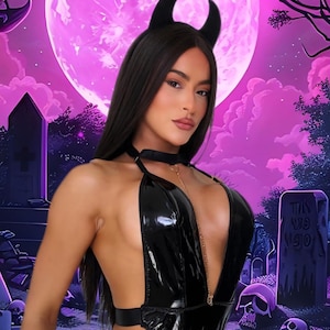 May include: A woman in a black devil costume with a black horn headband, choker, and a low-cut bodysuit. The background features a purple moon, tombstones, and skulls, creating a Halloween theme.