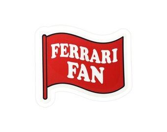 May include: A red flag-shaped sticker with the words "FERRARI FAN" in white, bold letters. The sticker has a white border and a black pole on the left side. The design is simple and eye-catching, perfect for fans of the Ferrari racing team.