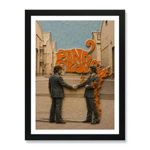 May include: A framed wall art piece featuring a textured, relief-style depiction of two individuals in suits shaking hands. One person is engulfed in orange flames. The words PINK FLOYD are displayed in large, orange, stylized lettering above them.