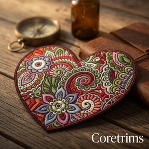 May include: A heart-shaped embroidered patch with a detailed floral design in red, green, purple, and orange. The patch has a dark red border and the text "Coretrims" at the bottom. The patch is on a wooden surface.