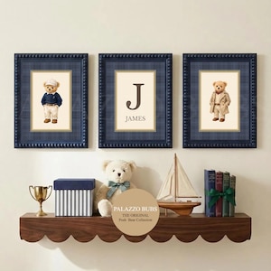 Puede incluir: Tres impresiones enmarcadas con bordes de cuadros azul marino. Cada impresión presenta un oso de peluche con diferentes atuendos o la letra "J" con el nombre "James". Una estantería debajo contiene un oso de peluche, libros y objetos decorativos.