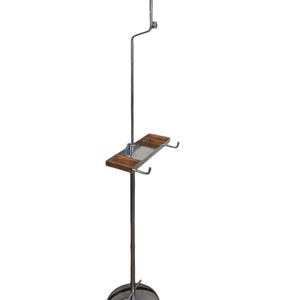 May include: A chrome hat stand with a wooden shelf and two hooks. The stand has a round base and a tall, adjustable pole with a brown leather hat form on top.
