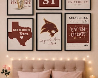 May include: A collection of framed prints featuring Texas State University logos and phrases, including "TX ST" and "Eat 'Em Up, Cats!" The prints are in black frames, displayed above a bed with pink bedding and a tufted headboard. Fairy lights and a candle add ambiance.