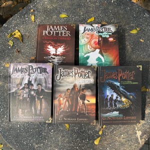 Op de afbeelding: Vijf hardcover boeken met de titel "James Potter" op de covers. De boeken hebben verschillende illustraties, waaronder een silhouet, een klok en een draak. De naam van de auteur, G. Norman Lippert, staat onderaan elk boek gedrukt.