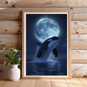 Puede incluir: Impresión artística enmarcada que representa una orca saltando bajo la luna llena. La obra muestra el cuerpo blanco y negro de la ballena contra un océano azul oscuro y un cielo estrellado. La impresión está en un marco de madera natural.