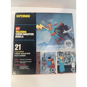 Puede incluir: Juego de carretes View-Master parlantes Superman GAF vintage. La caja muestra a Superman volando con un rayo y un avión. El juego incluye 21 imágenes parlantes de View-Master. La caja tiene el texto "Superman", "Talking View-Master Reels" y "Laugh and Learn".