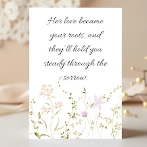 Może przedstawiać: Biała karta z napisem "Her love became your roots, and they'll hold you steady through the sorrow." Kwiatowe ilustracje akwarelowe w kolorze różowym, fioletowym i zielonym zdobią dół.