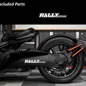 May include: Black motorcycle with the text "RALLY EDITION" in white. The motorcycle has black tires and orange accents. The image is taken indoors.