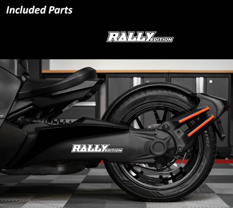 May include: Black motorcycle with the text "RALLY EDITION" in white. The motorcycle has black tires and orange accents. The image is taken indoors.