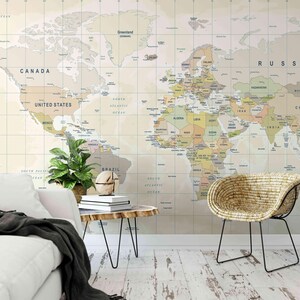 Peut inclure: Une grande carte du monde murale aux tons neutres sert de toile de fond dans un salon. Un canapé blanc, une table d'appoint en bois avec des pieds en épingle noirs et une chaise en osier sont au premier plan. Une plante en pot et un globe décoratif sont également présents.