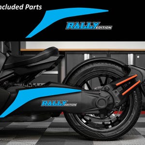 May include: A black and blue motorcycle with the text "RALLY EDITION" in white and blue. The image shows included parts with a blue design. The motorcycle has a black tire and orange accents.