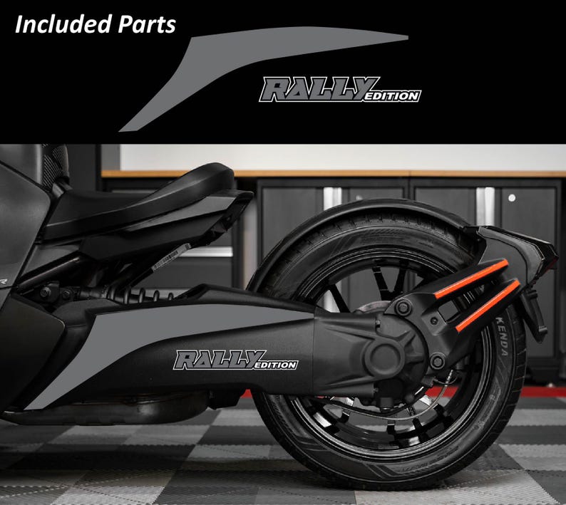 May include: A black and gray motorcycle with the text "Rally Edition" on the side. The image shows the rear wheel and suspension components, with orange accents. The words "Included Parts" are at the top.