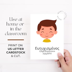 May include: A white card with a cartoon illustration of a smiling boy with brown hair and a yellow shirt. The card has the Greek word "&Epsilon;&upsilon;&tau;&upsilon;&chi;&iota;&sigma;&mu;έ&nu;&omicron;&sigmaf;" and the English word "HAPPY" printed on it. Text on the card reads "Use at home or in the classroom."