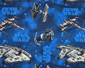 May include: A blue fabric featuring a repeating pattern of Star Wars spacecraft, including X-wings, TIE fighters, and the Millennium Falcon. The words "STAR WARS" are also printed on the fabric. The background is a dark blue with white star-like specks.
