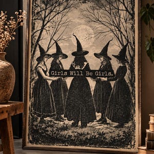 May include: A rectangular framed wall art print featuring a black and white illustration of five figures in pointed hats and long dresses standing in a circle in a forest under a full moon, with the text Girls Will Be Girls printed across the center.