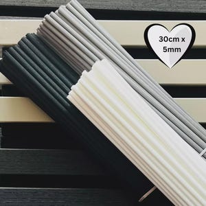 Puede incluir: Un conjunto de varillas de madera en tonos negro, gris y blanco. Las varillas están dispuestas en diagonal, con un gráfico en forma de corazón que indica las dimensiones de 30 cm x 5 mm. Adecuado para manualidades o proyectos de bricolaje.