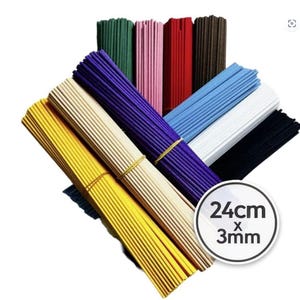 Pode incluir: Pacotes de varetas de incenso em várias cores, incluindo amarelo, roxo e verde. Cada pacote é preso com um elástico. A imagem inclui um círculo branco com as dimensões de 24 cm x 3 mm.