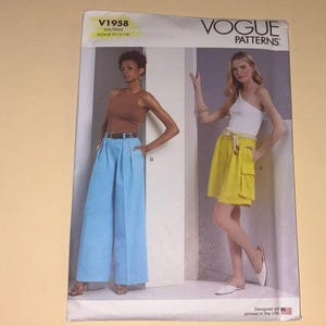 May include: Vogue Patterns V1958 sewing pattern envelope featuring two garment styles: wide-leg light blue trousers with a belt and a yellow knee-length skirt with a tie waist and side cargo pockets. The pattern is sized for A5 6-10-12-14.