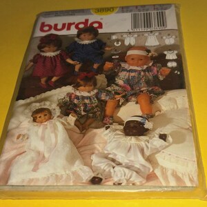 May include: A Burda sewing pattern packet featuring images of several dolls in various outfits. The dolls are dressed in dresses and other garments. The packet is sealed in clear plastic and set against a yellow background.